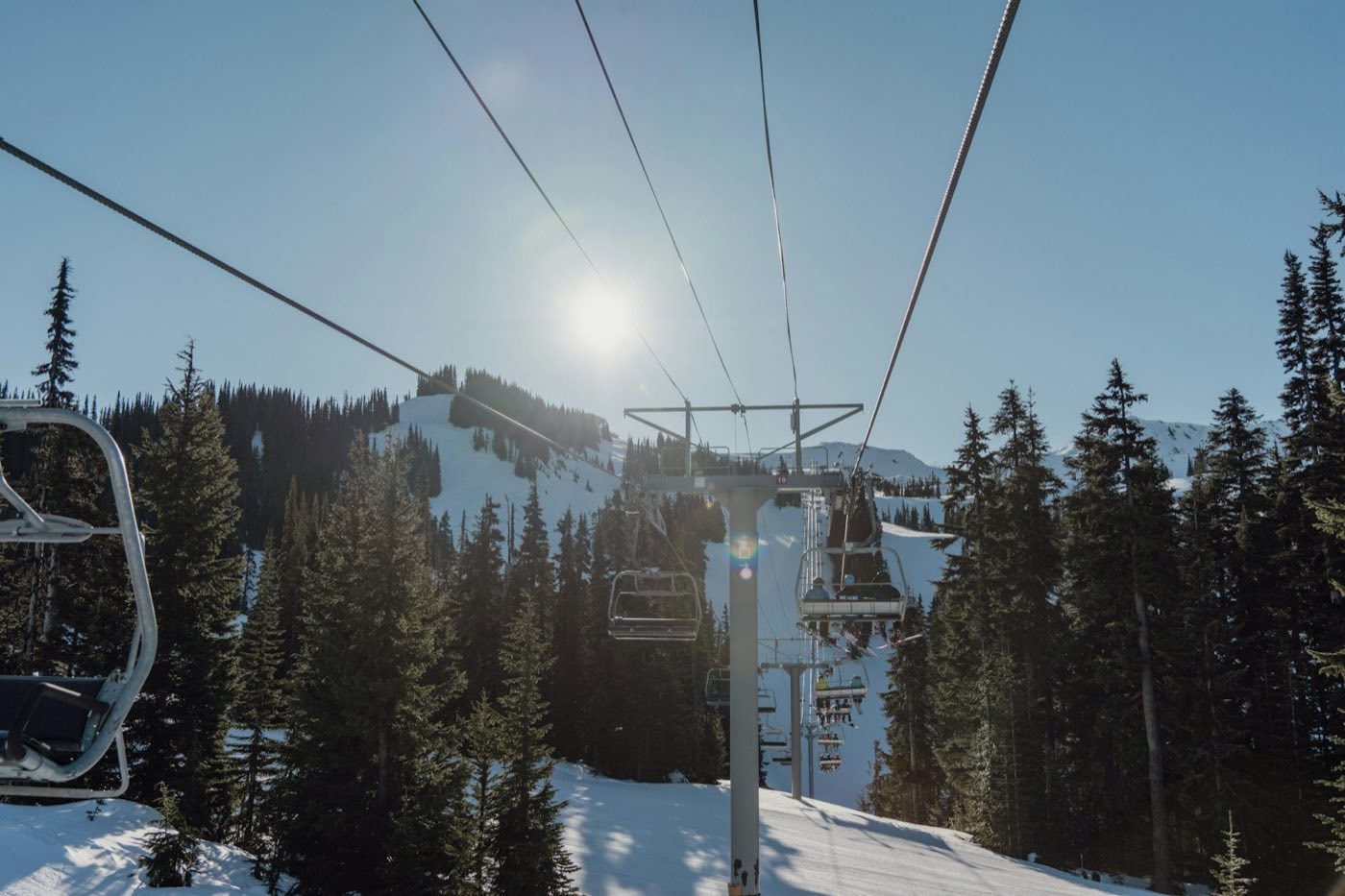 A chairlift line climbing a snowy slope under a bright winter sun