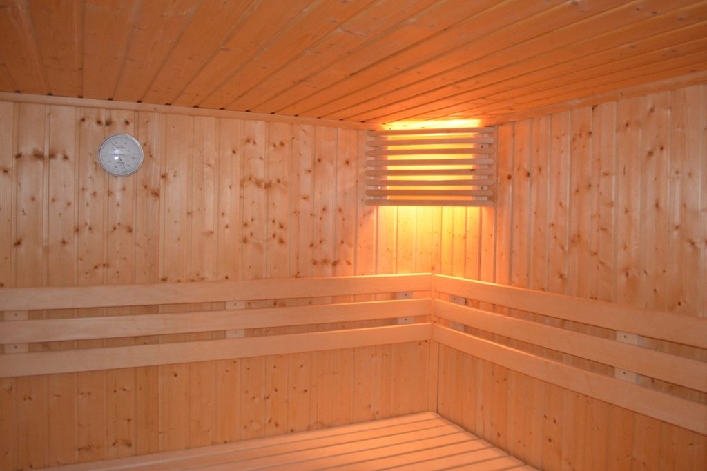 A clean pine sauna cabin with tiered benches and a soft wall light